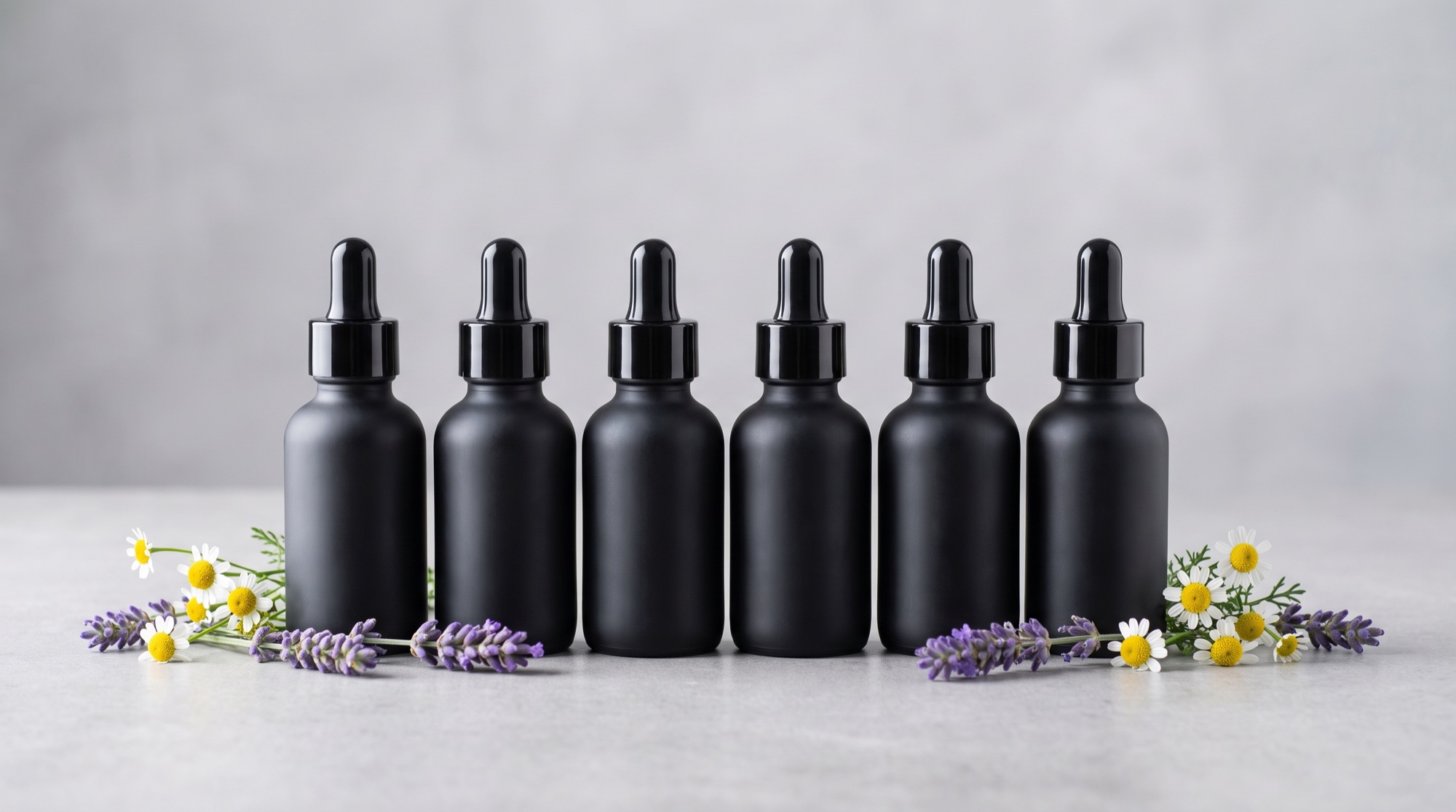 Fila de seis frascos de pre-fórmulas de Flores de Bach Manoma sobre superficie clara